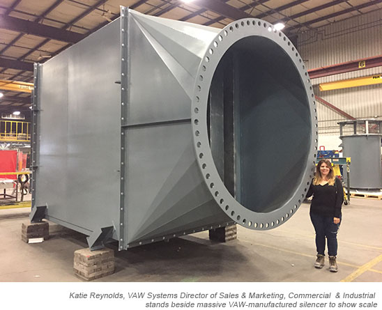 Katie Reynolds, VAW  Systems Director of Sales & Marketing, Commercial & Industrial stands beside massive VAW-manufactured silencer to show scale